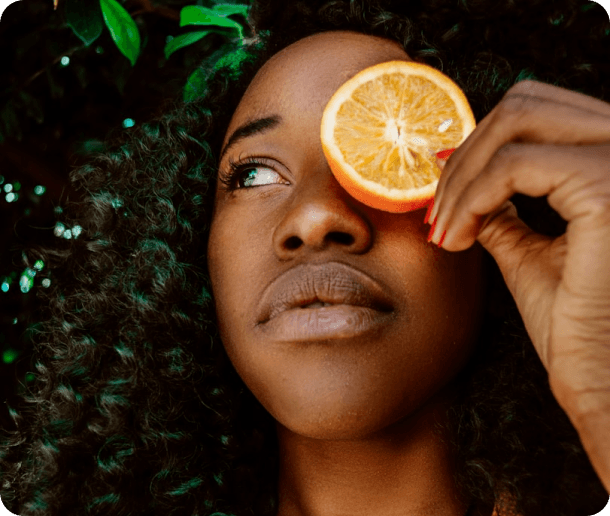 A woman holding a slice of orange over one eye